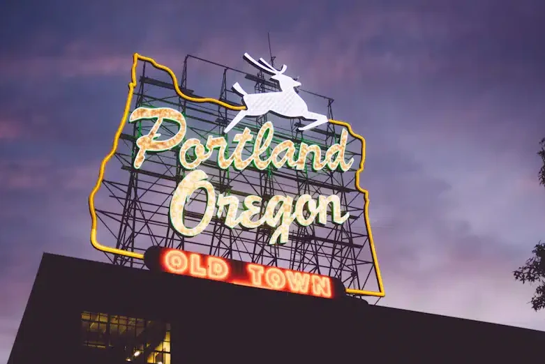 A neon sign with a deer that says Portland, Oregon